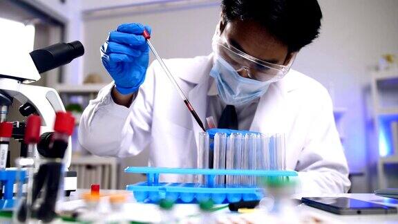 亚洲科学家正在做一些研究在实验室的试管中检查液体