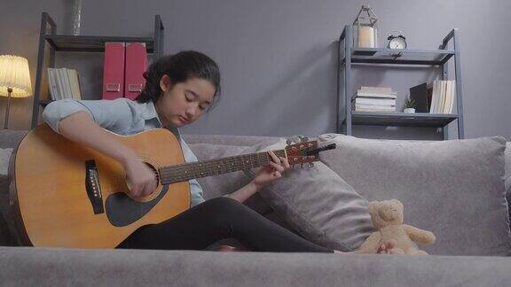 快乐的少女在家里的客厅里弹吉他创造性的爱好