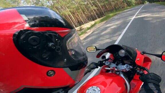 一个骑摩托车的人戴着头盔在路上骑着一辆红色的摩托车
