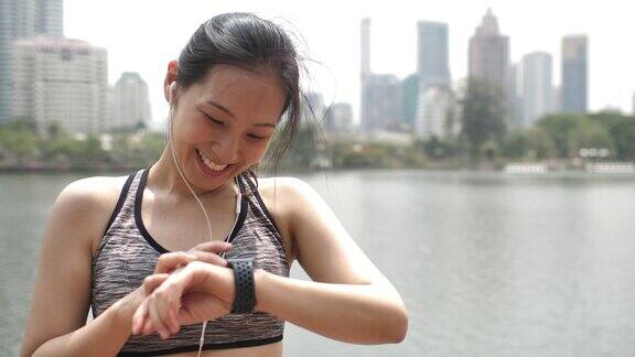 运动的年轻女性在智能手表上监控她的跑步表现