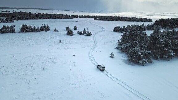 空中拍摄的白色汽车在被雪覆盖的道路上行驶