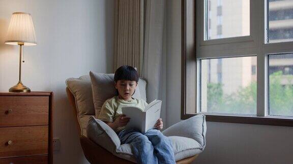 小男孩坐在窗边看书
