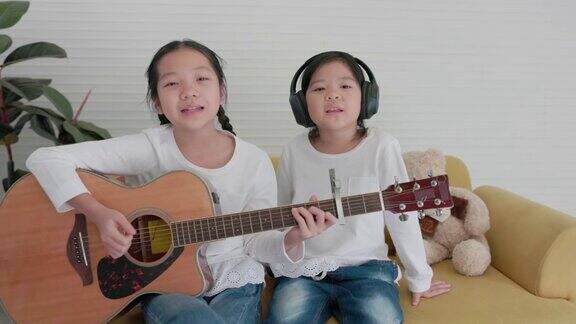 两姐妹在客厅里玩得很开心在舒适的家中你们可以一起弹吉他和唱歌