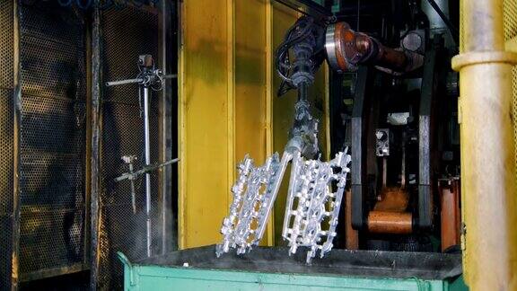 在一家汽车厂机器人正在将汽车发动机的金属零件放入水中冷却