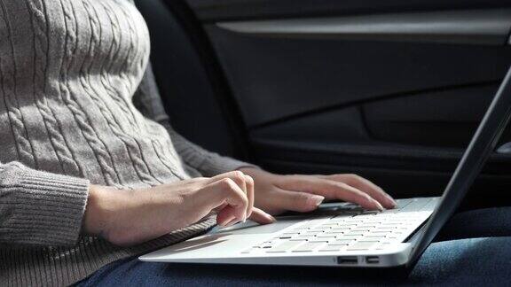 SLOMO女人在车里使用笔记本电脑打字键盘