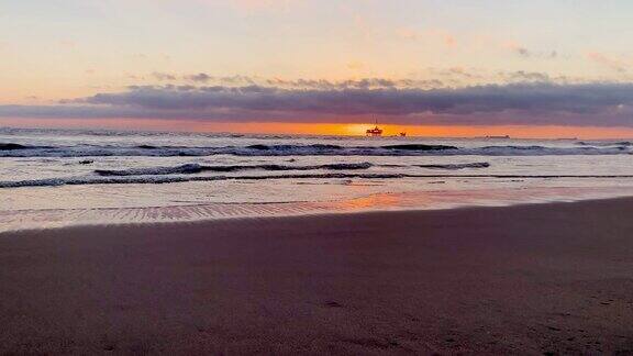 从亨廷顿海滩上的一个美丽的景色一个戏剧性的日落在一个石油钻机平台近海