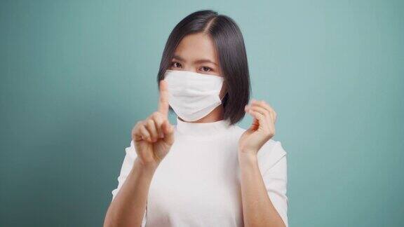 不要摸你的脸亚洲妇女戴着卫生口罩显示手停止标志孤立地站在蓝色背景卫生保健4k的视频