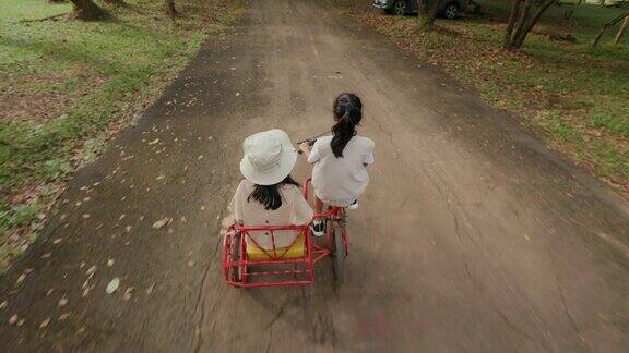 小女孩和姐姐一起骑着三轮车和载货自行车