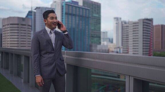 成功的亚洲华人商人在金融大楼外用智能手机交谈