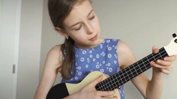 可爱的女孩在家里学习弹奏尤克里里