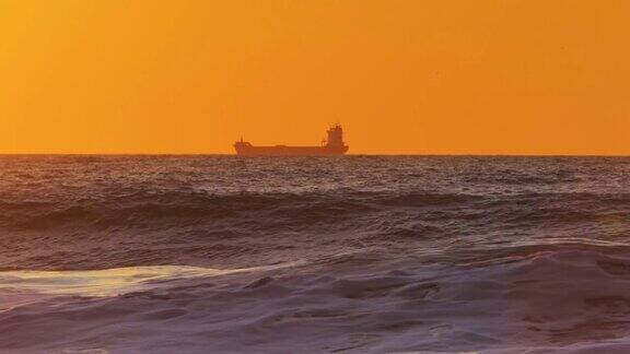 海上日出启航的货船早在水中金色的天空
