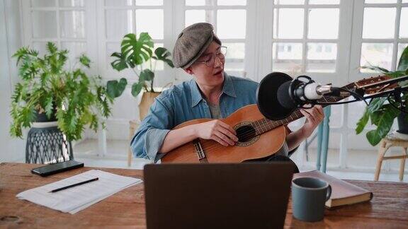 年轻的亚洲音乐家练习弹吉他而写自己的音乐在家里的办公室