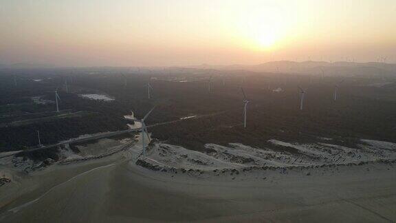 海滩上雄伟的风力发电厂的航空摄影日落视图