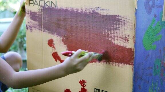 一个亚洲小女孩正在用画笔在纸盒上画画