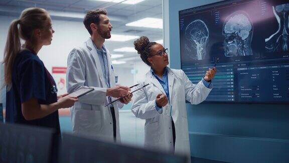 医学科学医院实验室会议:不同团队的神经学家神经科学家神经外科医生咨询电视屏幕显示MRI扫描与脑图像讨论治疗方法新药治疗