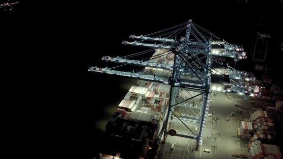 鸟瞰图装载集装箱的货船在夜间装卸集装箱时停靠在港口的泊位上