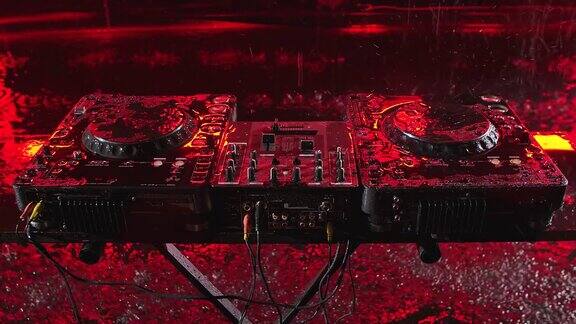 音频混音控制器在一个黑暗的演播室与红色照明DJ工具在倾盆大雨中前视图关闭了慢动作
