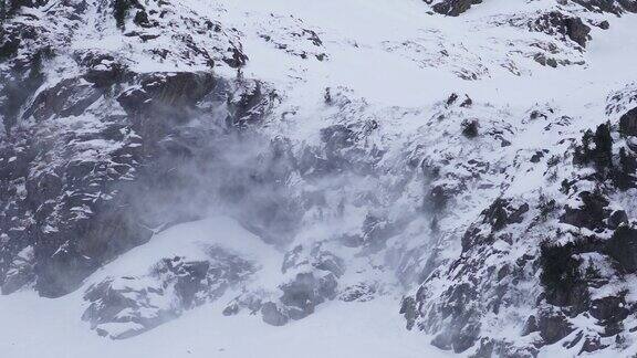 在多雪的岩石冰川上雪从悬崖上被吹走