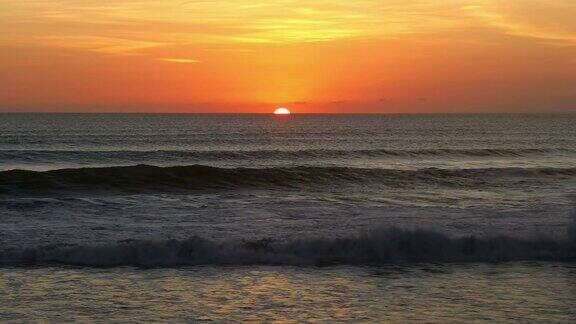 日落在地平线上海浪冲上岸