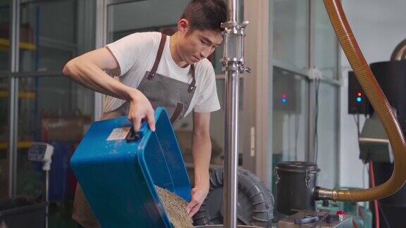 亚洲中国工匠将生咖啡豆装载到咖啡烘焙机器上为咖啡烘焙过程做准备