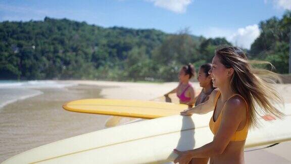 在夏日阳光明媚的日子里一群亚洲女子手持冲浪板走向大海