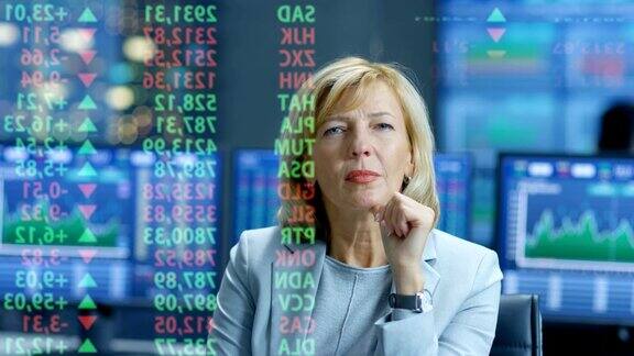 股票市场女性高级经理看着预测的股票号码和图表在她满是屏幕和数据的房间后面