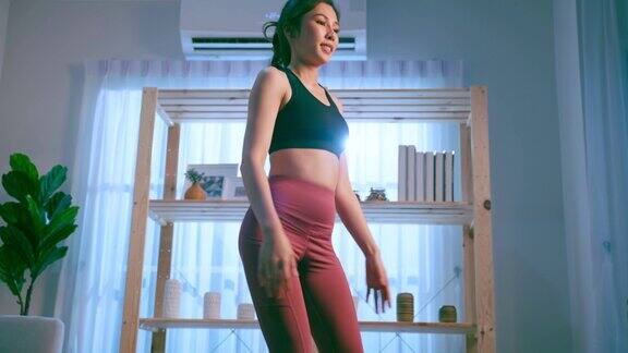 亚洲年轻美丽活跃的运动女性在家里做有氧运动漂亮的女孩穿着运动服在家里的客厅里用垫子花空闲时间健身保健