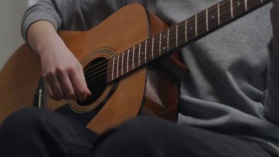 一个少年在明亮的客厅里弹吉他房间里有美丽的阳光女人在室内作曲这位艺术家弹原声吉他这个女孩正在独自练习一种乐器