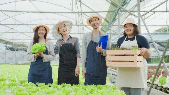 亚洲农民在蔬菜水培农场工作的肖像小组迷人的年轻农业男女感到自豪和自信的工作后在温室与幸福然后看着相机