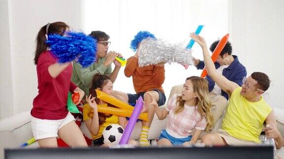 一群亚洲男女朋友一起在家里看电视上的足球运动