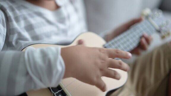 亚洲男孩在家练习吉他和尤克里里学习与幸福