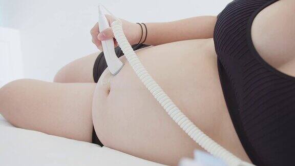 孕妇在自己的肚子上做超声波探头移动使用胎儿多普勒装置监听胎儿心跳装置