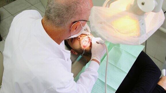牙医在男人的牙齿上钻孔