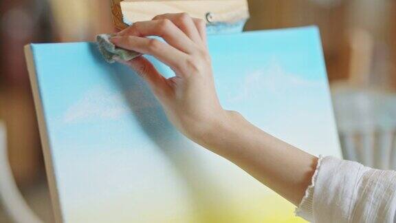 女艺术家在艺术工作室用海绵在画布上作画