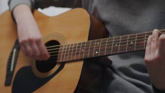一个青少年放学后在家学习新的原声吉他和弦特写镜头