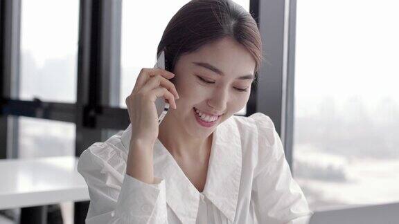 年轻快乐漂亮的亚洲女员工在手机上谈笑风生