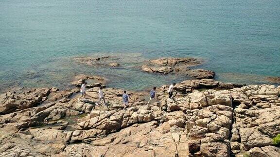 年轻的亚洲成年人在海边的岩石上行走