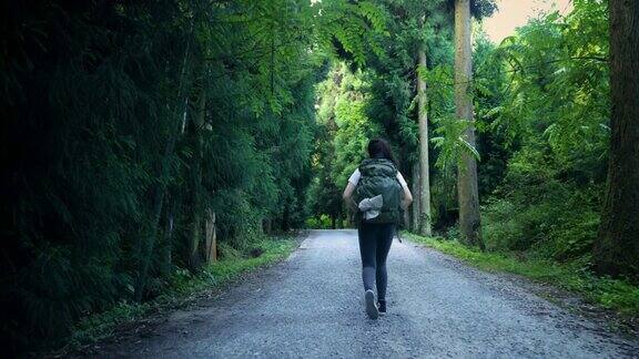 背着背包的女人走在森林路上