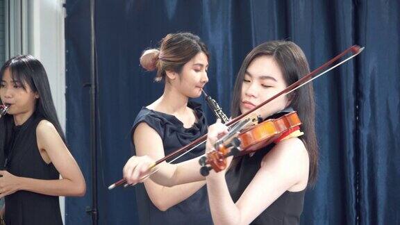 青少年女性交响乐团在表演期间与小提琴家的重点
