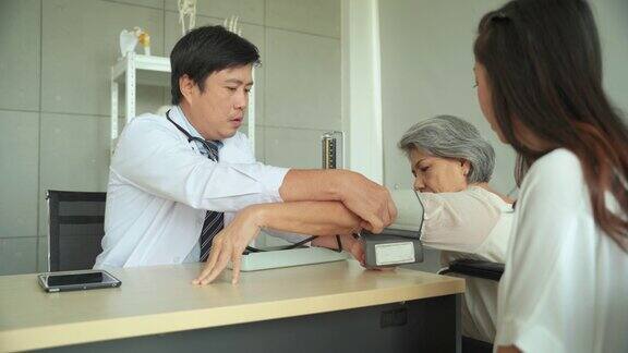 在医院里男医生戴着血压计给一位老年女病人看