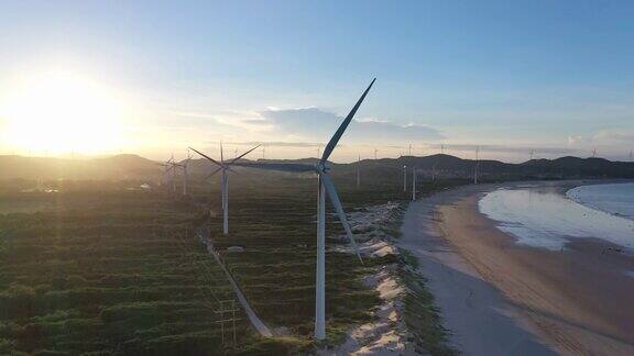 日落时海滩上风力发电场的无人机视角
