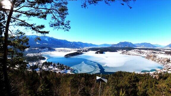 在奥地利阿尔卑斯山的Faak湖上从一座小山上俯瞰冬季的全景风景如画的湖泊被高山环绕群山映在平静的湖面上Taborhoehe他泊