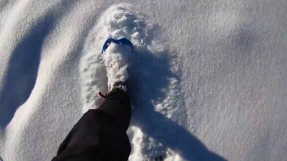 在刚下过雪的地方踩雪山路POV徒步旅行者的观点靠近雪鞋踩在新雪上