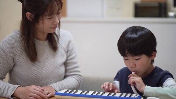 母亲陪着孩子练习键盘口琴
