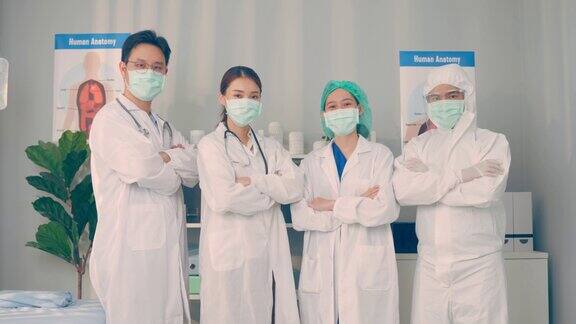 一群医生和护士戴着口罩对镜头微笑着交叉手臂