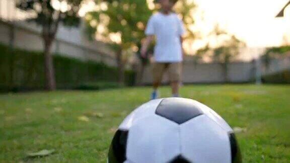 亚洲小孩在公园里踢足球在房子的后院假期和健康