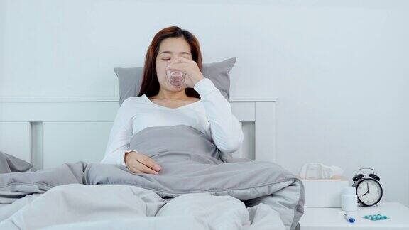 一名年轻的亚洲女子在家中卧病在家吃药的4K视频