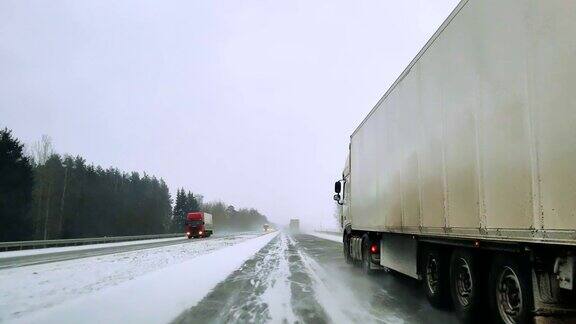 在可怕的多雪多风的天气里重型货车在公路上行驶透过挡风玻璃的视野-驾驶员视角移动视频