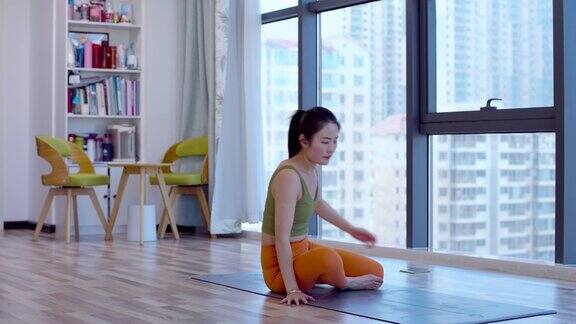年轻的亚洲女子在客厅练习瑜伽