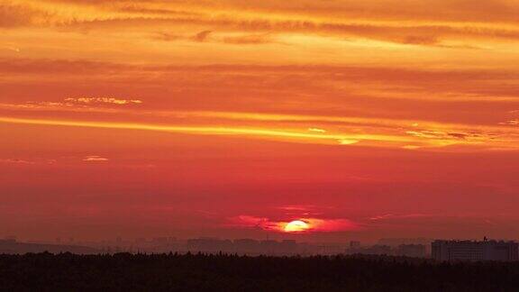 一轮红艳艳的大太阳在夕阳的天空中掠过建筑物的屋顶城市的风景傍晚的天空在明亮的阳光下笼罩着黄昏的城市